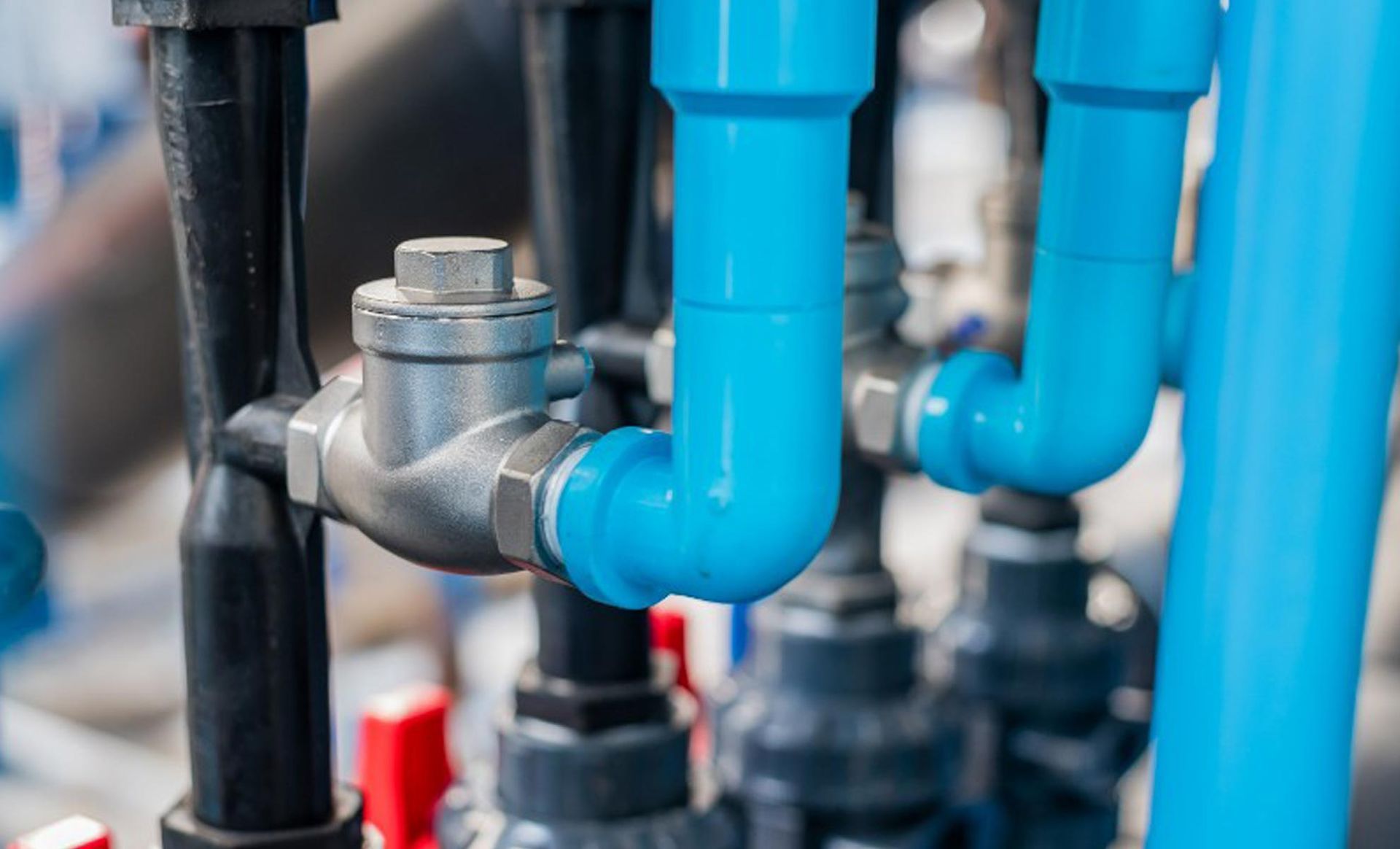 A metal backflow preventer valve on blue and black supply pipes